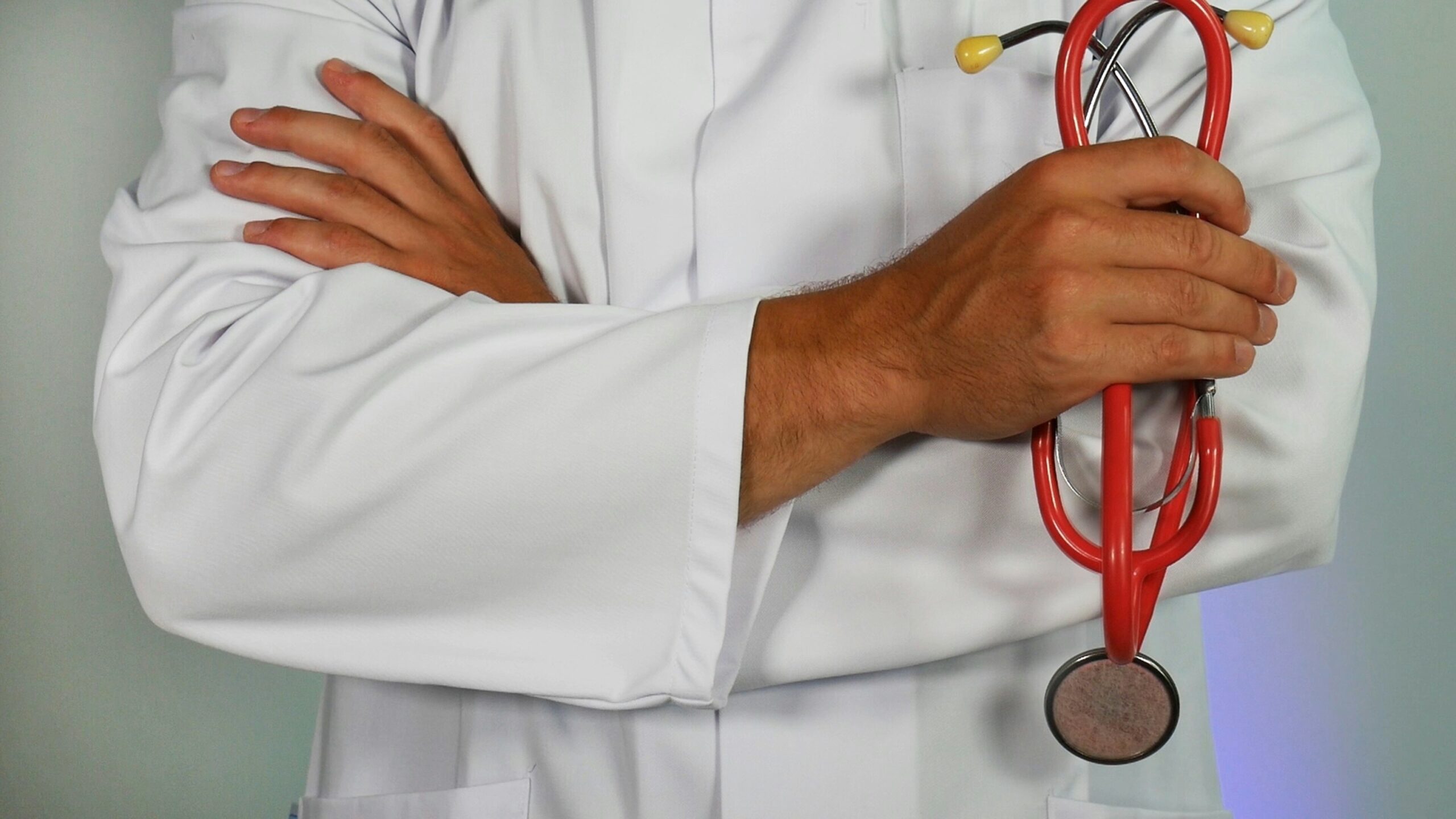 medical website design featured image - toros of a doctor with arms crossed holding a red stethoscope